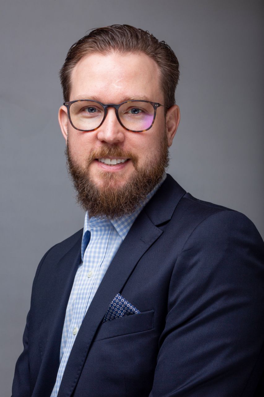 Huber Mastelari, VP Service Contracts & Connectivity bei International, wearing glasses, a blue shirt and a navy blue coat. 