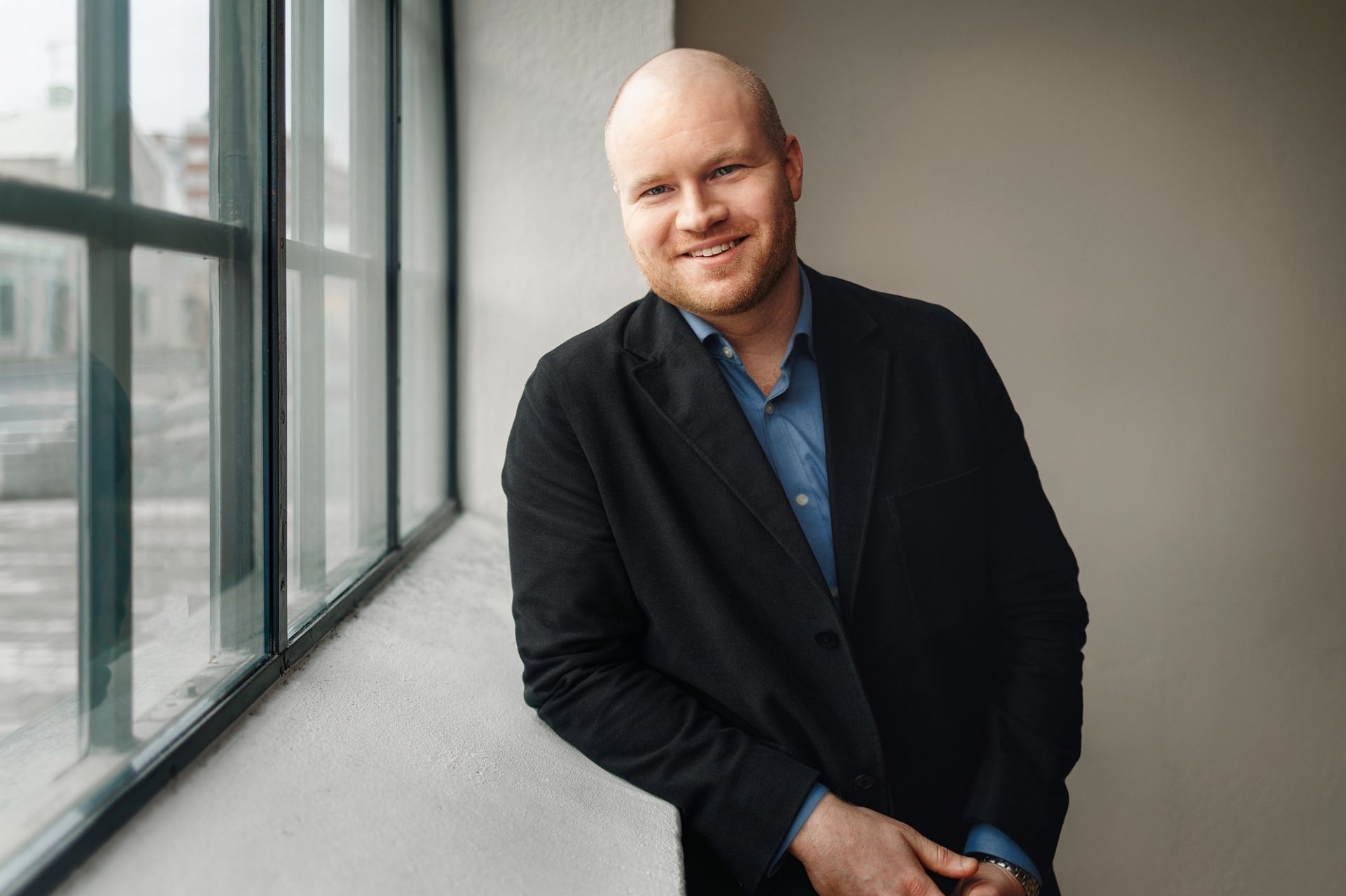Oscar Duse, Senior Portfolio Manager at Group Product Management, smiling. He is wearing a blue shirt and black coat. 