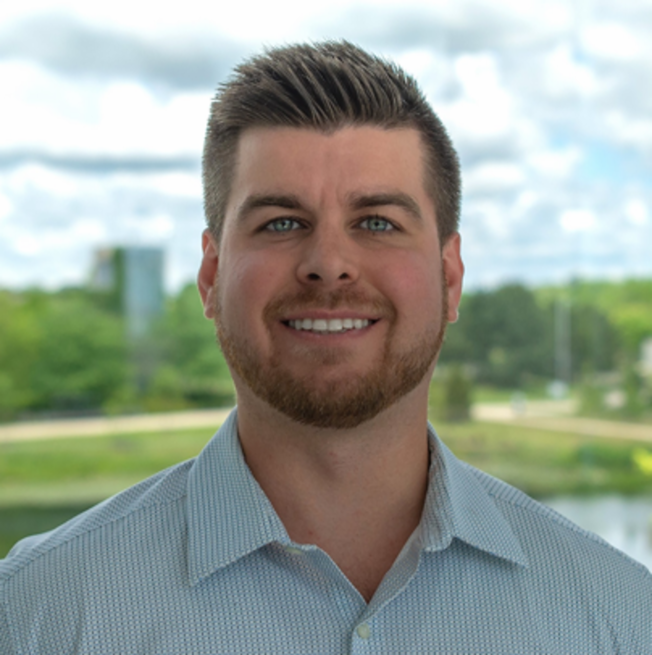 Thomas Yaeger, Senior Product Marketing Consultant at International, smiling wearing a blue shirt. He is in front of a landscape background. 