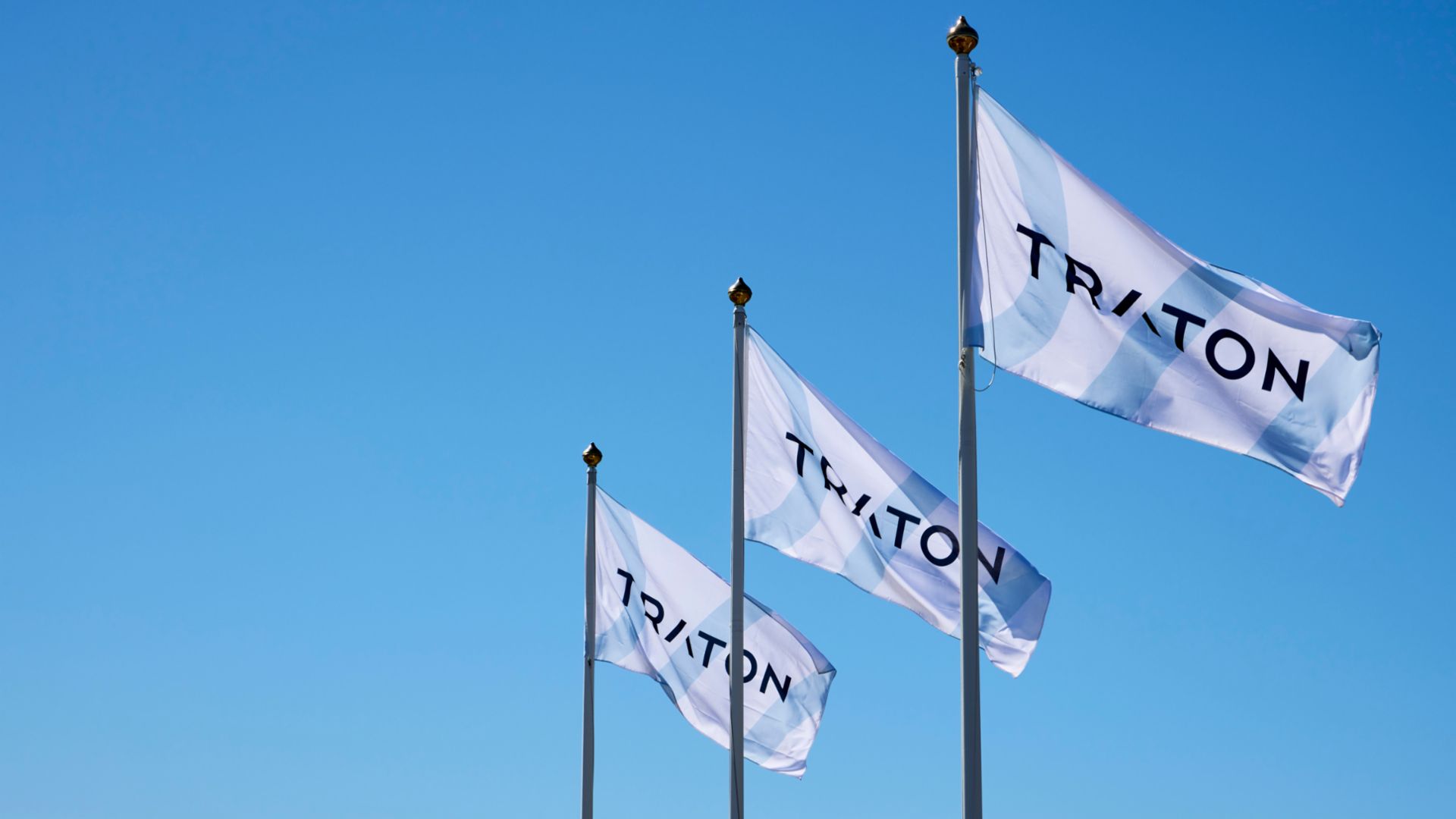 3 Flaggen mit dem Logo von TRATON nebeneinander im Wind