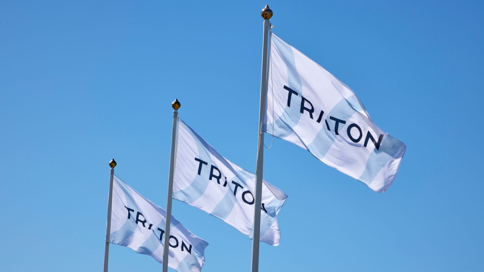  3 Flaggen mit dem Logo von TRATON nebeneinander im Wind