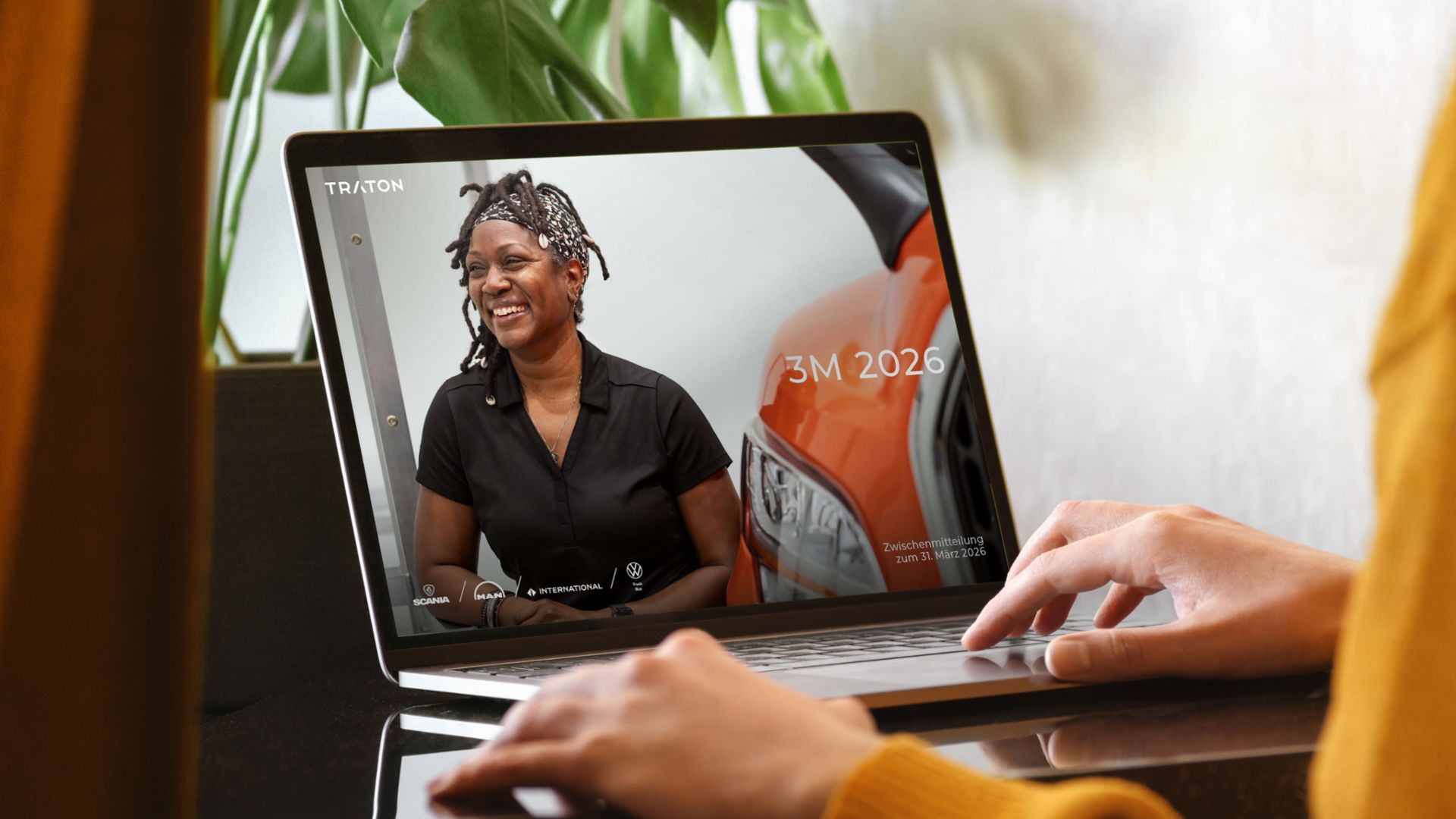 Hände einer Person, die einen Laptop betrachtet. Auf dem Bildschirm wird das Cover des TRATON 3M-Berichts angezeigt.