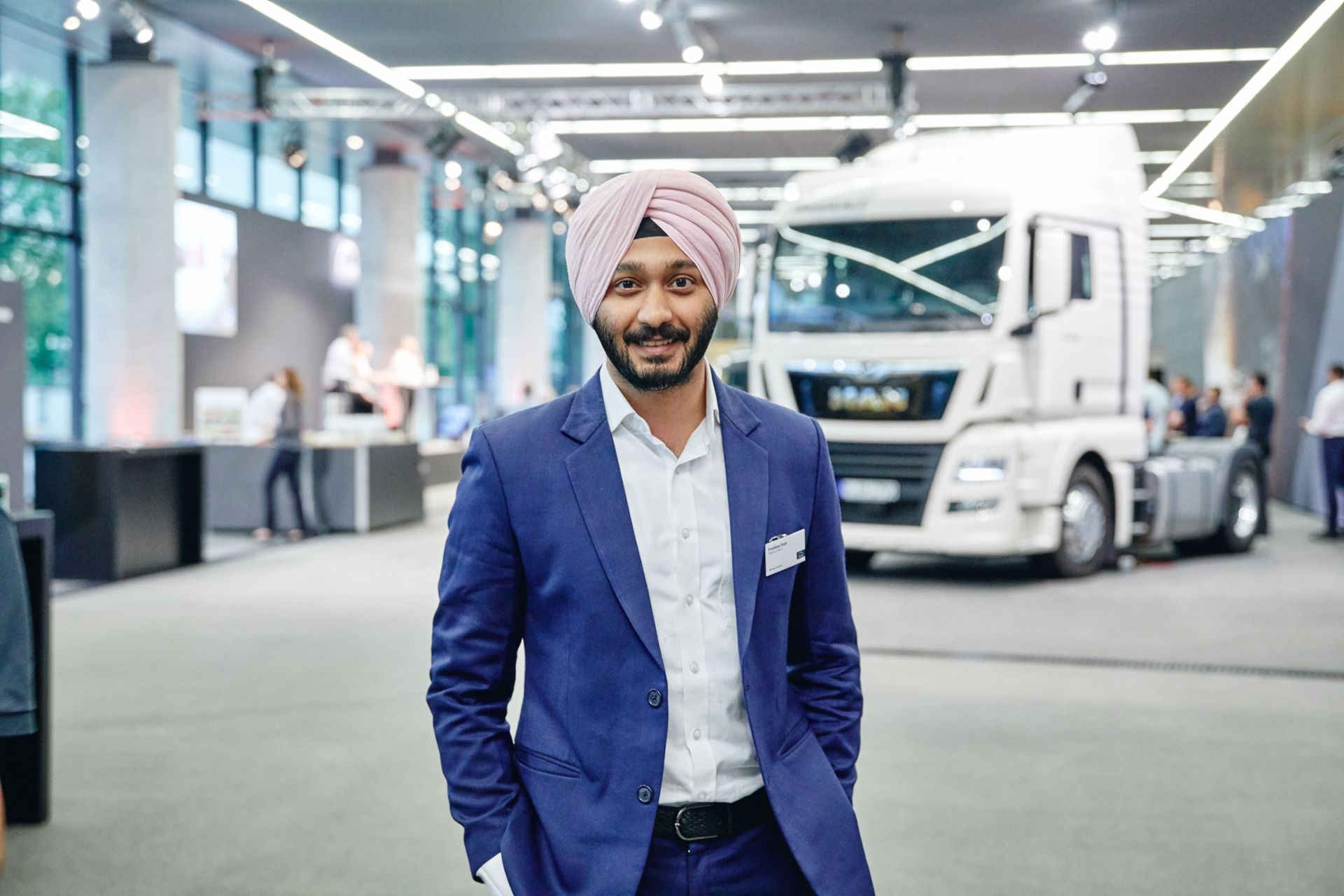 Prabhdeep Singh, one of the three founders of Stanplus, standing in a brightly lit hall in front of a MAN truck.