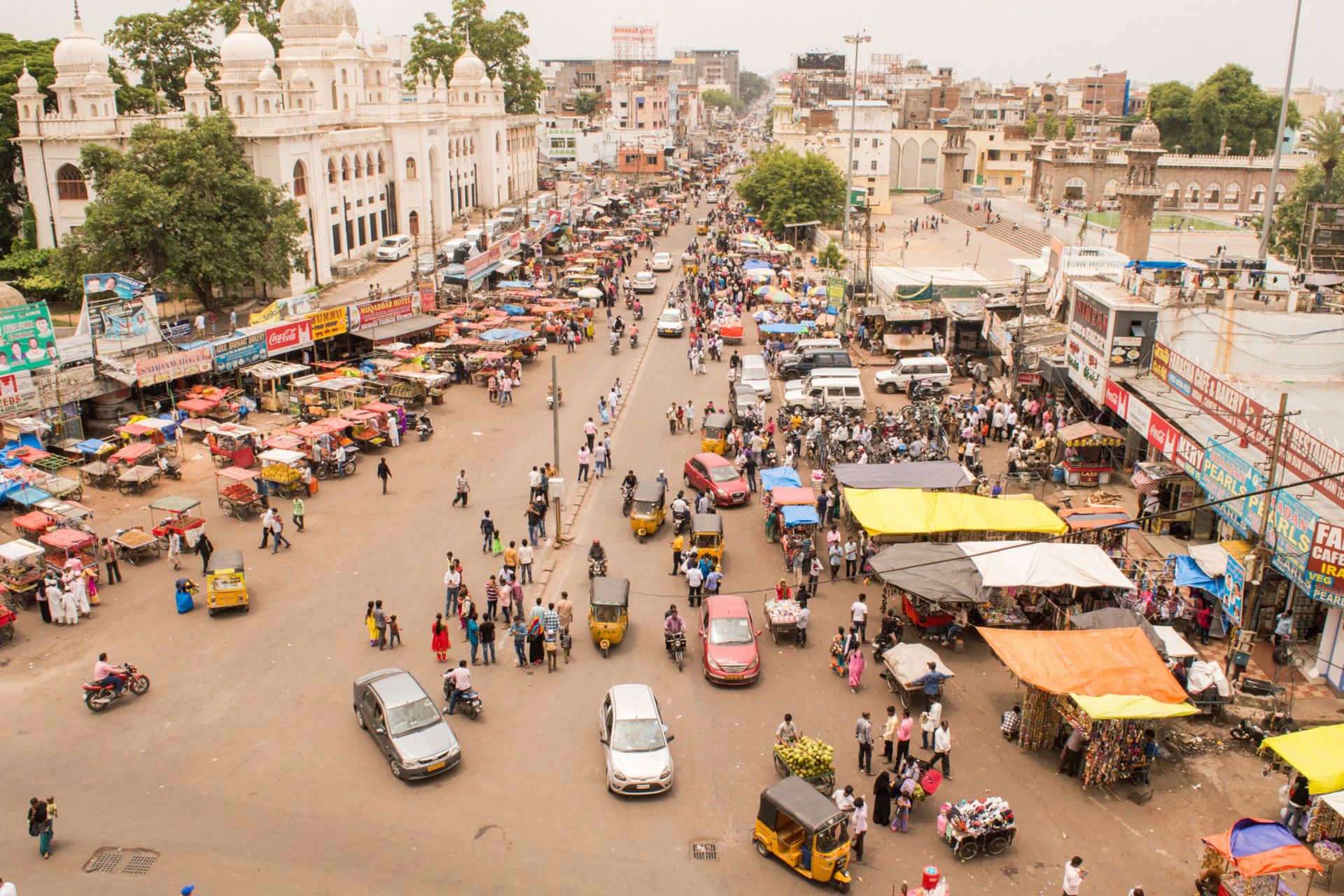 Ein Markt in Indien zwischen dem eine stark befahrende Straße lang führt
                 