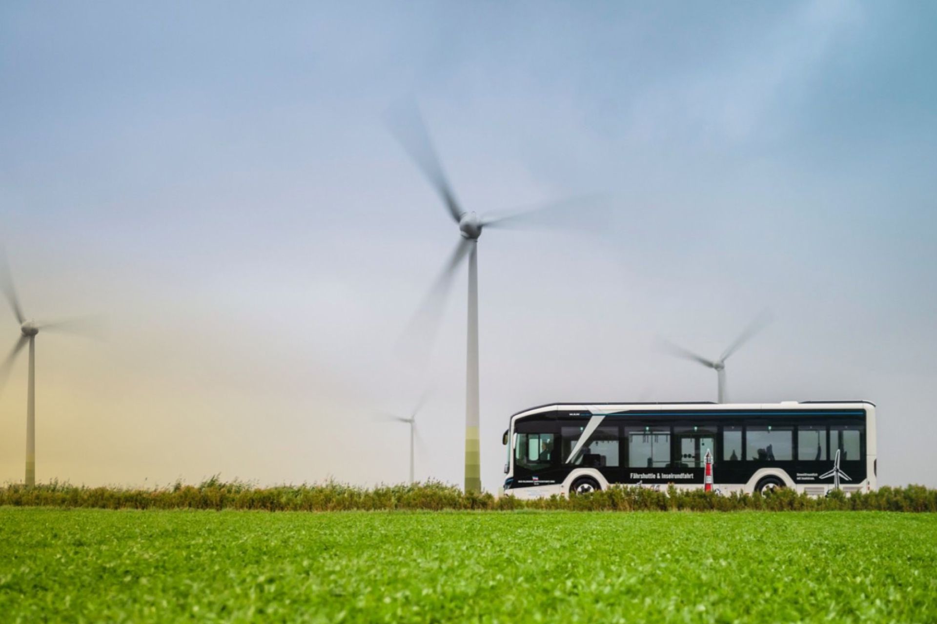 Bus faehrt an Windkraftanlagen vorbei
                     