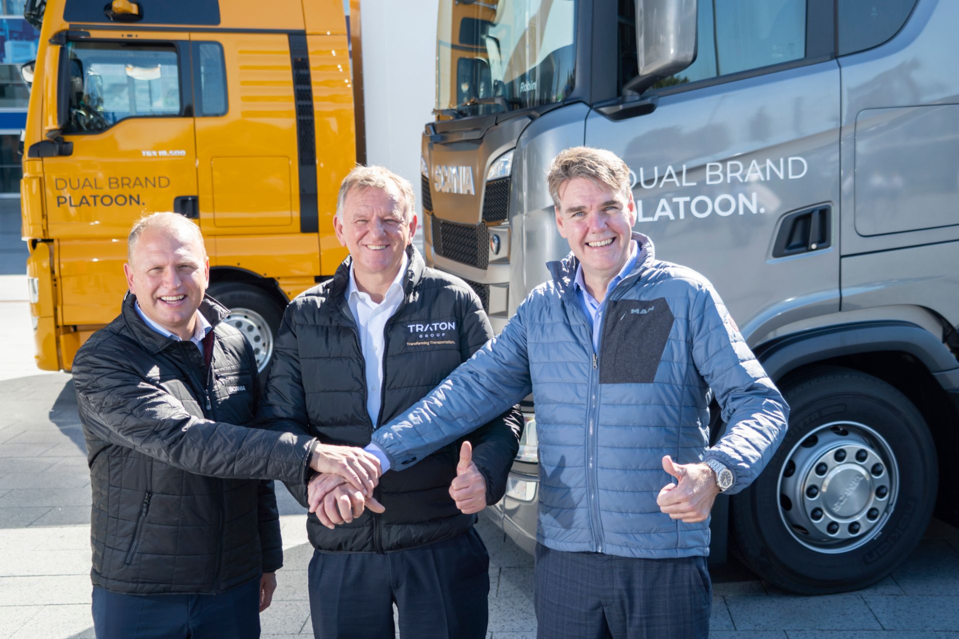 Henrik Henriksson, Andreas Renschler und Joachim Drees blicken lächelnd in die Kamera und geben sich die Hand.
                 