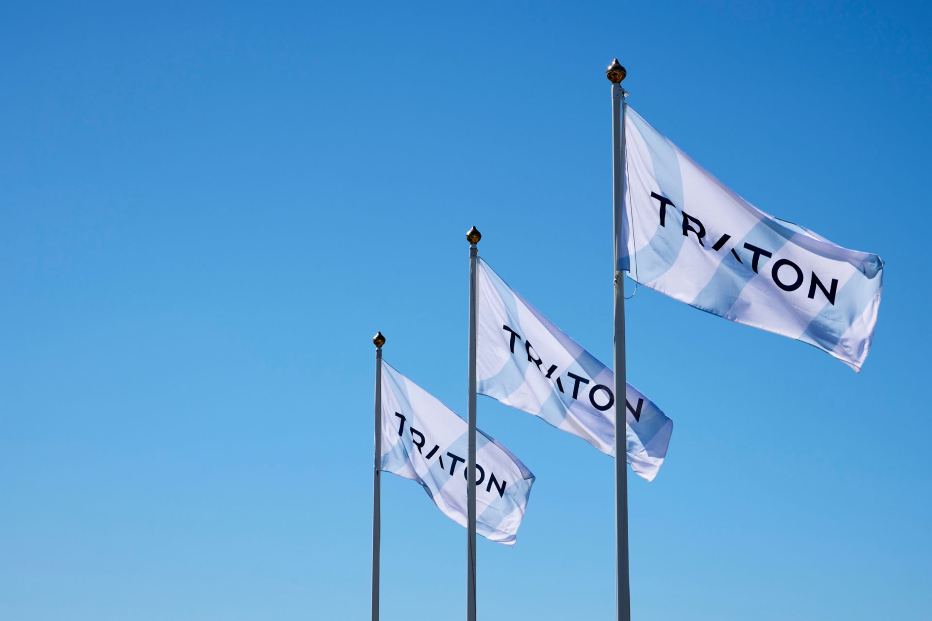 3 Flaggen mit dem Logo von TRATON nebeneinander im Wind