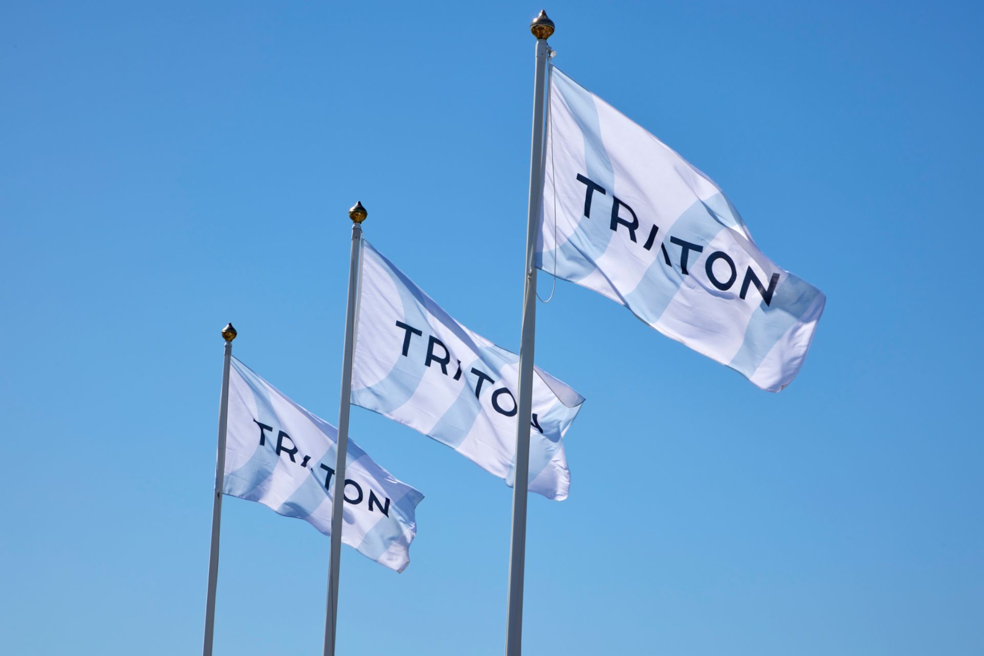  3 Flaggen mit dem Logo von TRATON nebeneinander im Wind