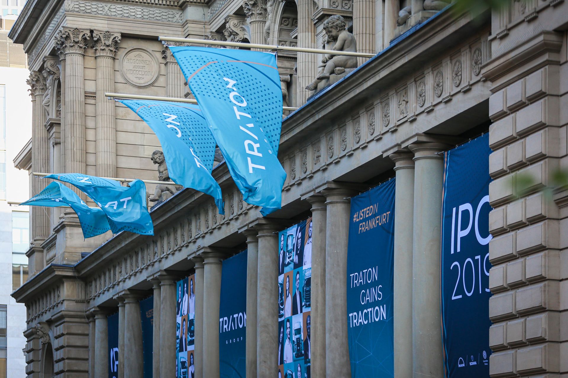 Light blue TRATON flags, as well as dark blue TRATON banners, hanging in front of the Frankfurt Stock Exchange
                 