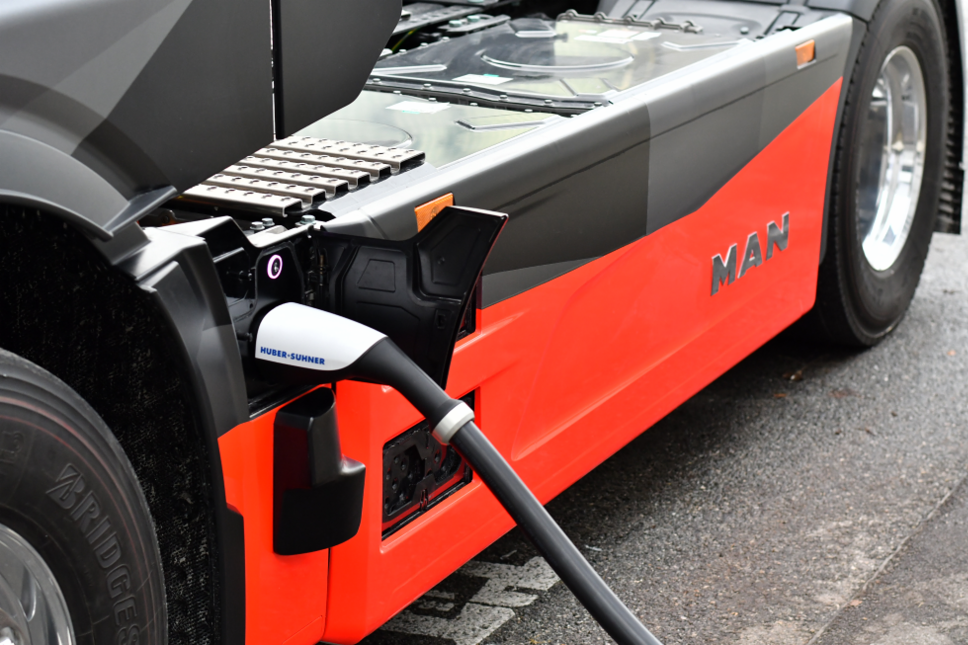 Ein roter MAN eTruck wird an einer Megawatt-Ladestation aufgeladen.
                 