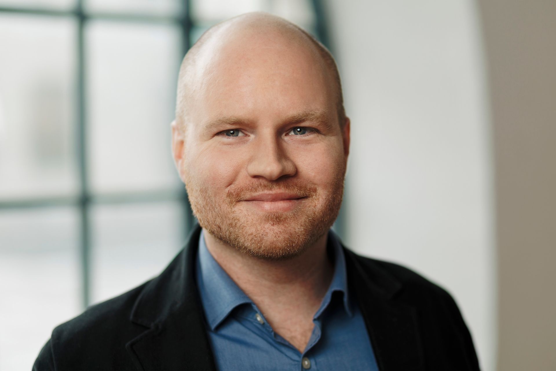 Oscar Duse, Senior Portfolio Manager at Group Product Management, smiling. He is wearing a blue shirt and black coat. 