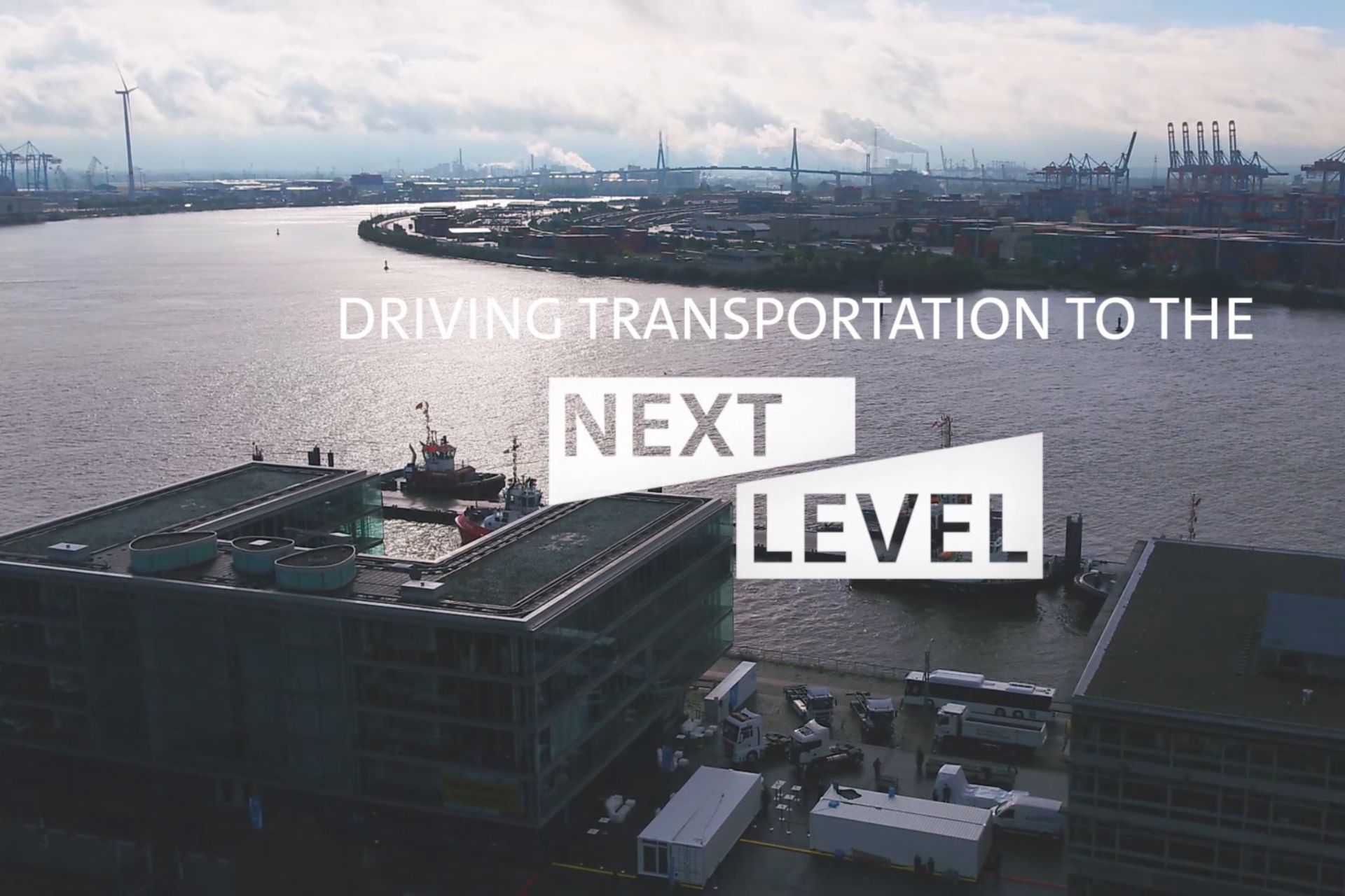 Text saying driving transportation to the next level over image of industrial harbour 
                 